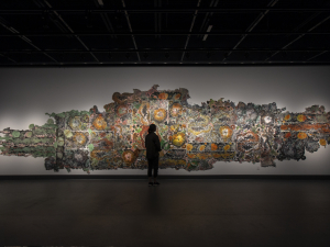 Chantal Harvey is silhouetted against the backdrop of her 15-foot mural representing lichens